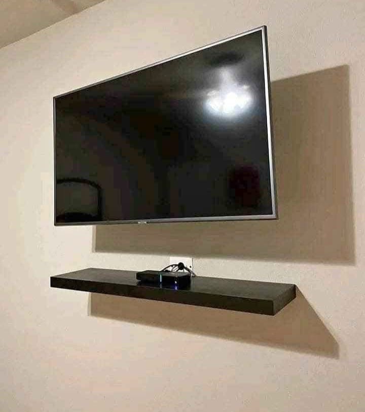 Wall mounted TV above a floating shelf with a decoder