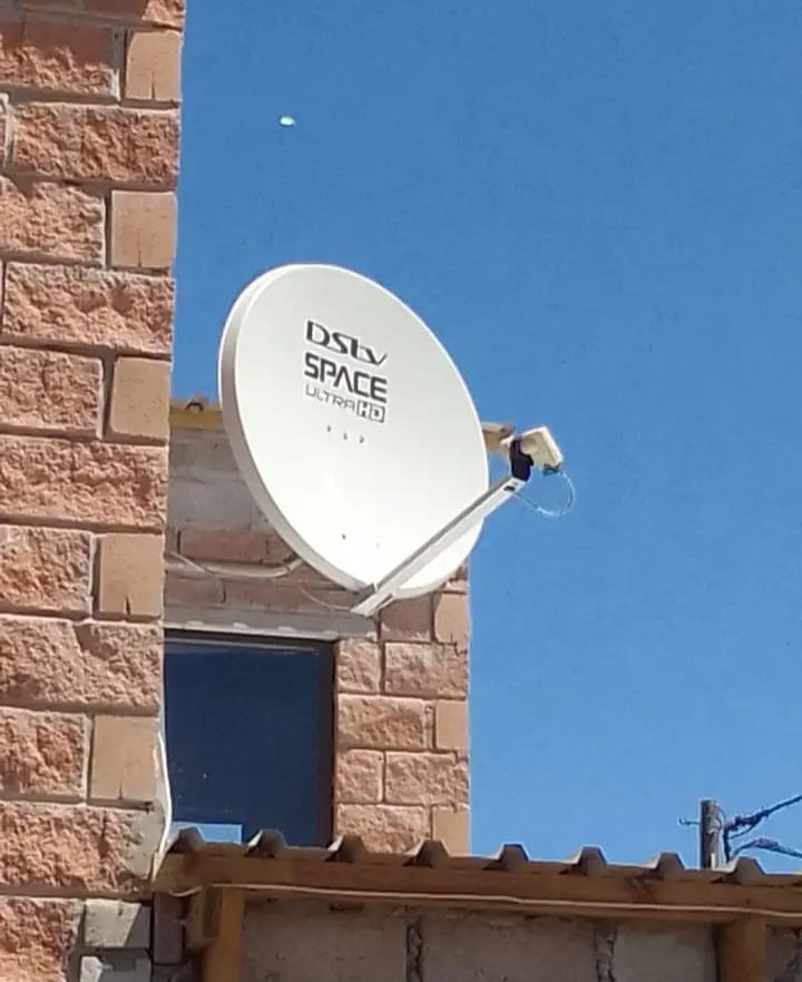 DStv Space Ultra HD satellite dish mounted on a face-brick wall